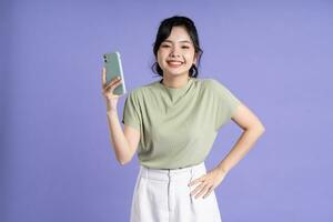 Portrait of beautiful asian woman using smartphone on purple background photo