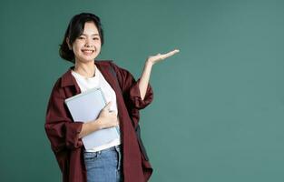 retrato de un hermosa asiático estudiante en un verde antecedentes foto