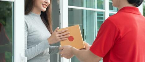 Happy smiling woman receives boxes parcel from courier in front house. Delivery man send deliver express. online shopping, paper containers, takeaway, postman, delivery service, packages photo