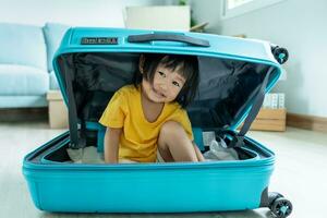 little asian children kid playing hide and seek in travel bag, Adorable child having fun in the home. happy family have fun with kids, activity, learning, activity, game, meditation photo