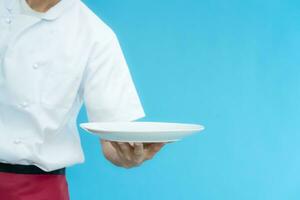 cooking, culinary, male chef holding empty plate, male chef in toque and jacket over blue background, professional, show, serve, cooking, , gourmet, food, service, restaurant, presenting photo