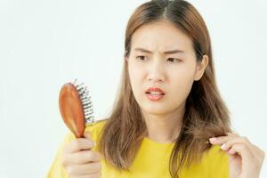 Asian woman very sad and upset looking at damaged hair, hair loss, hair thinning problem, vitamin deficiency, baldness, postpartum, biotin, zinc, menstrual or endocrine disorders, hormonal imbalance photo