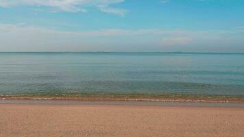 Ocean waves gently hit the sandy beach and the blue sky is beautiful. video