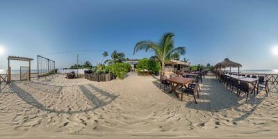 360 hdri panorama with coconut trees on ocean coast near tropical shack or open cafe on beach with swing in equirectangular spherical seamless projection photo