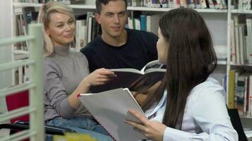 Jeune femelle étudiant souriant à le caméra tandis que parlant à sa copains à bibliothèque video