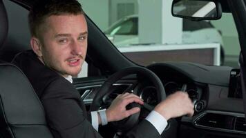 Bearded businessman holding out car key to the camera, sitting in new automobile video