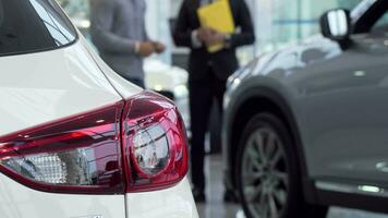 Selective focus on a car, salesman talking to the customer on the background video