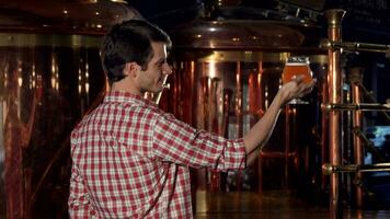 Rear view shot of a happy brewer showing thumbs up after examining beer video