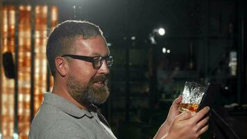 Bearded man waiting for his friend at the bar, using smart phone video