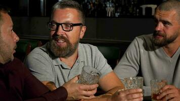 Group of mature male friends laughing and talking over glass of whiskey at the bar video