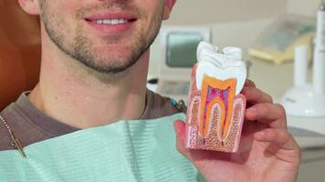 Man with white healthy teeth smiling, holding dental mold at the clinic video