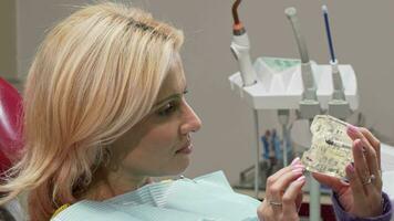 Mature woman smiling to the camera, holding dental mold at the clinic video