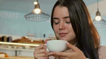 bajo ángulo Disparo de un hermosa mujer sonriente a el cámara, participación taza de café video