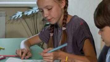 Young girl and boy drawing together in class video