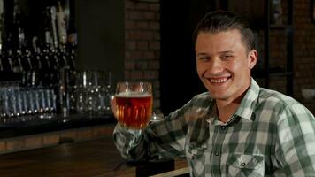 Beau content homme souriant grillage le sien Bière verre à le caméra video