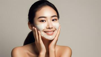 Asian woman using skincare product. Taking face cream to apply on facial skin photo