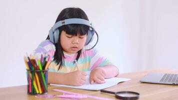 Asian female student wearing headphones studying online from home video