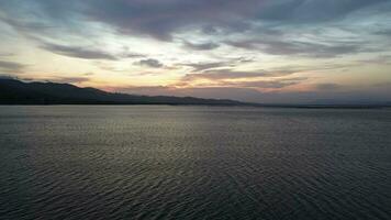 Aerial view over the water of the lake with sunset views and sun reflections. Aerial view of lake. Flying over water. Flight over calm lake surface video