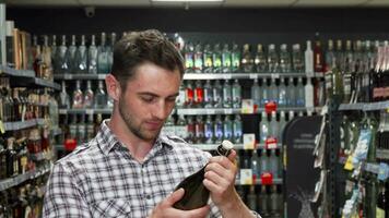 Handsome young man smiling to the camera while choosing wine video