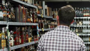 Rearview shot of a man examining wine on the shelves at the supermarket video