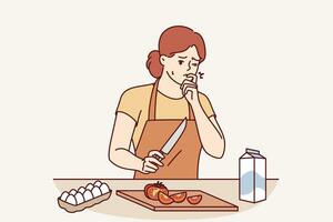 Woman housewife cooking dinner cut finger and is trying to stop bleeding, standing in kitchen photo