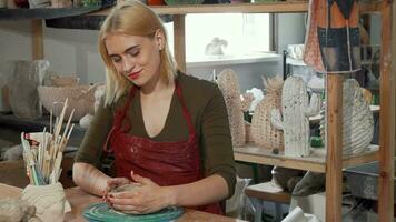 Gorgeous young woman smiling while working with clay at the workshop video