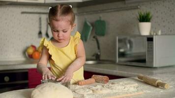 un pequeño niña prepara pasteles desde masa y harina a hogar en el cocina.masa cocinar, niño educación, hogar comida dulce pasteles video