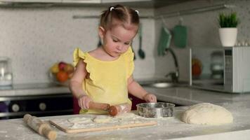 feliz criança 2 anos velho prepara pastelaria a partir de massa e farinha dentro a cozinha às a mesa.massa cozinhando, criança educação, casa comida, doce pastelaria. video