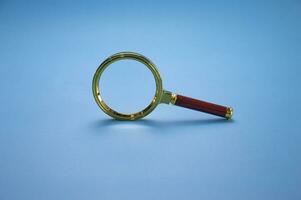 Magnifying glass with colored frame The handle is made of wood on a blue background. photo