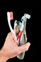 a person holding three different toothbrushes photo