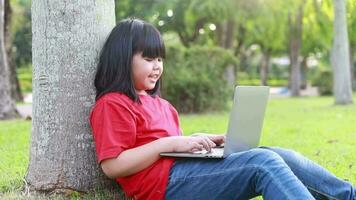 niña en rojo camisa utilizando ordenador portátil en público parque video