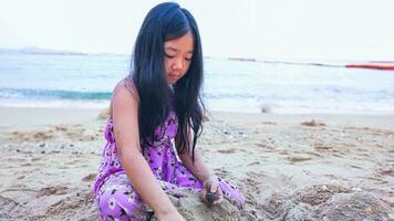 A little girl enjoying herself in the sand on a Thailand beach where the Gulf of Thailand is located photo