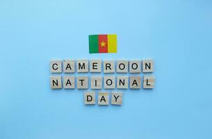 January 1, flag of Cameroon, Independence Day in Cameroon, minimalistic banner with the inscription in wooden letters on a blue background photo