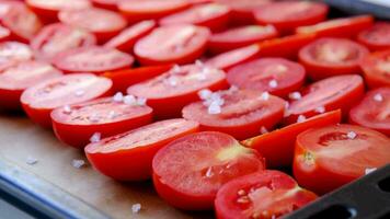 salt falling on tomatoes in baking tray , closeup, slow motion video