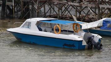 Small passenger motor boat with nobody inside docking, parking or floating somewhere near the beach. photo