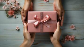 AI generative. Female hands holding pink gift box on wooden background. Top view. photo