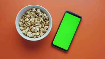 top view of smart phone and popcorn on table video