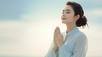 Asian woman practicing yoga with her hands together under a vibrant sky. Generative AI photo