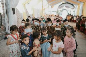 a group of children wearing masks and standing in a room photo