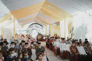 a wedding ceremony in a tent with people sitting photo