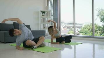 joven asiático Pareja practicando yoga juntos a hogar video