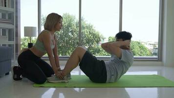 Young Asian Trainer Helping Man to do Sit up exercise at home video