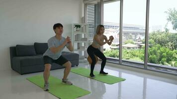 Jeune couple faire des exercices par Faire s'accroupir ensemble à Accueil video