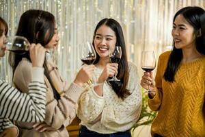 Cheerful friends enjoying home Birthday holiday party. Asian Friends cheering drinking red wine celebrating New Year party. photo