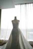 Beautiful White Wedding Dress on a White Mannequin in The Room With Large Window photo