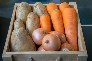 cebolla, Zanahoria y patata en madera caja con luz de estudio. foto