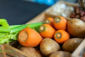 Zanahoria y patata en madera caja con luz de estudio. foto