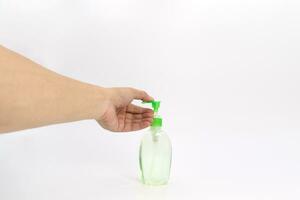 Asian mand hand holds a gel alcohol pump bottle and ready to pushes on it. It's an isolated object on the white clear screen in studio light. photo