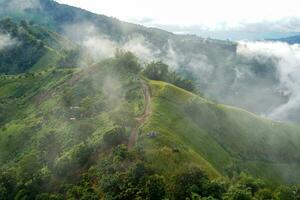 A view from the top of a high mountain overlooking the path to the villagers' farms and the beautiful mist in the rainy season in northern Thailand. Soft and selective focus. photo