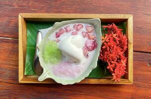 Sweet-noodles ,water chestnut and coconut ice cream in coconut milk syrup are Thai desserts. Eat together, th e taste is sweet and refreshing, served on a wooden tray de corated with flowers. photo